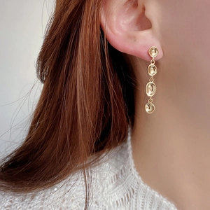 Macro shot of 925 sterling silver long tassel gold plated irregular concave disk earrings