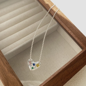 Gros plan du pendentif cœur en argent avec zircons colorés dans un écrin en velours