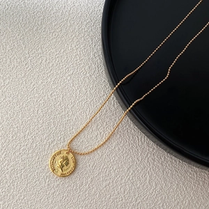 Macro detail of gold coin pendant necklace with portrait relief on textured background
