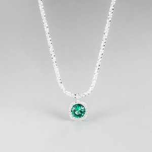 Detail of silver necklace featuring an emerald green gemstone with micro-paved diamonds