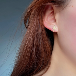 Close-up of a matte gold star stud earring in 925 sterling silver on a woman's ear
