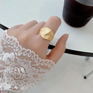 Macro shot of matte gold wide band ring with irregular brushed texture on a model