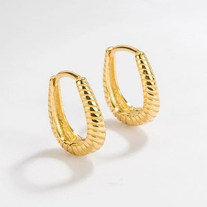 Detail of twisted s925 silver hoop earrings with gold plating and textured spiral finish