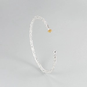 Detailed shot of S925 silver cuff with embossed floral patterns and gold crown accent