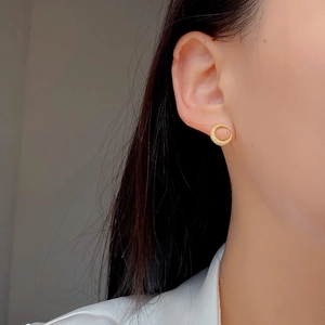 Close-up of matte golden crescent moon stud earrings worn by a model in a side profile view