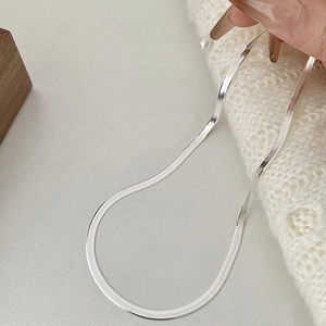 Détail d'une chaîne serpent plate en argent 925 sur un tissu en maille blanche