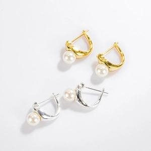 Detail view of gold and silver U-shaped hoop earrings with elegant white pearls