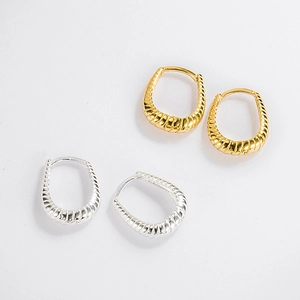 Detailed view of textured twisted gold and silver hoop earrings in a vintage croissant style