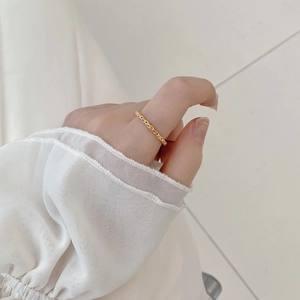 Détail d'une bague chaîne minimaliste en or 18K portée avec des manches à volants