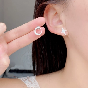 Close-up of asymmetrical 925 sterling silver moon and star studs on ear