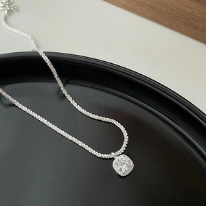 Close-up of S925 sterling silver handbag pendant with cushion-cut zircon on black plate