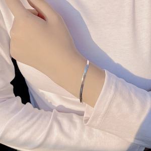 Close-up of a minimalist S925 sterling silver flat snake chain bracelet on a wrist