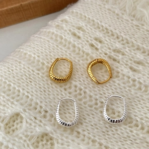 Detail of vintage twisted S925 silver hoop earrings on a white knit background