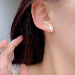 Close-up of a 925 sterling silver frosted star stud earring worn on a female ear