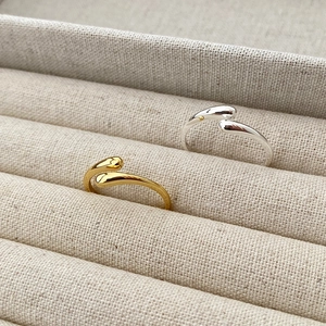 Macro detail of minimalist S925 sterling silver water drop rings in gold and silver finish