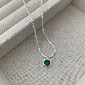 Macro shot of S925 sterling silver chain with a green gemstone halo pendant