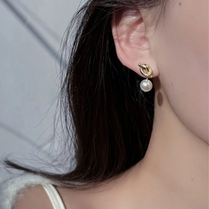 Close-up of elegant gold knot pearl drop earrings worn to show style and size details