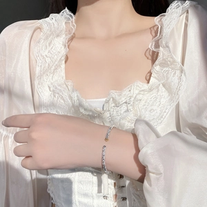 Close-up of S925 silver open bangle featuring embossed floral patterns and gold bead accents