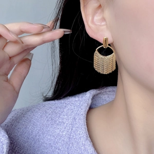 Close-up of golden tassel drop earrings in S925 sterling silver on model's ear