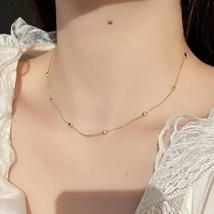 Gros plan d'un collier de perles dorées élégant porté sur un col en dentelle blanche