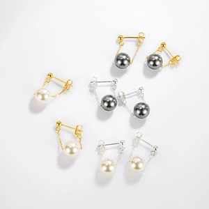 Detail view of round pearl stud earrings with dangling chains in gold and silver plating