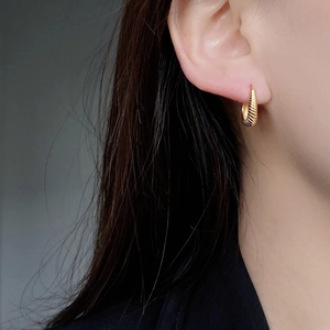 Classic golden braided hoop earrings with wheat twisted texture on a model side view
