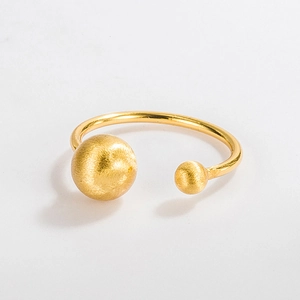 Macro detail of open gold ring featuring brushed metal spheres and polished band texture