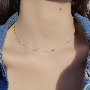 Gros plan d'un collier chaîne perlé en argent 925 minimaliste porté sur le cou avec denim