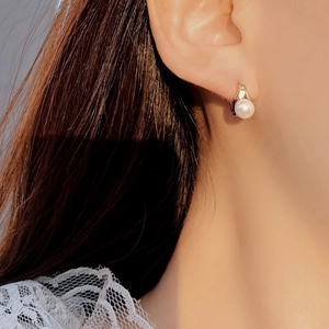 Close-up of elegant gold S925 silver pearl hoop earring worn by a female model