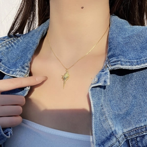 Detail of a minimalist gold seashell pendant necklace worn on a casual denim jacket