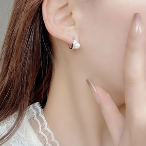 Close-up of elegant S925 silver hoop earrings with round pearls on a female model