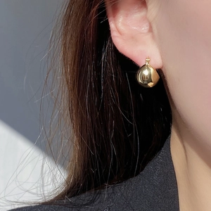 Close-up of a polished gold teardrop earring showcasing smooth mirror-like metallic finish