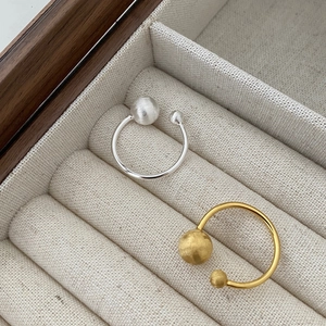 Detailed view of brushed silver and gold geometric ball rings on a fabric jewelry box