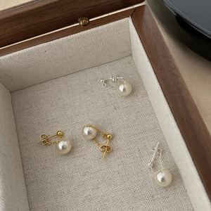 Detail of gold and silver floating pearl earrings displayed in a premium wooden jewelry box