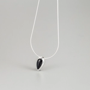Vue détaillée du pendentif goutte avec pierre noire sur une chaîne serpent argentée