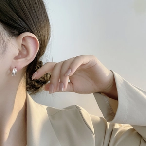 Gros plan de boucles d'oreilles créoles C argentées à trois couches sur un mannequin