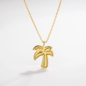 Macro shot of gold palm tree pendant necklace with fine textured tropical tree details