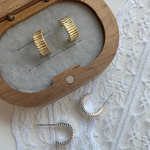 Detailed view of S925 silver earrings with pleated gold texture and silver C-shape design