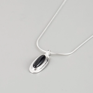 Macro detail of S925 silver necklace with black oval agate stone and orbital pendant