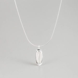 Detailed view of an oval pendant with a white gemstone on a sleek snake chain necklace