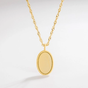 Detail of matte gold oval pendant on twisted rope chain against white background