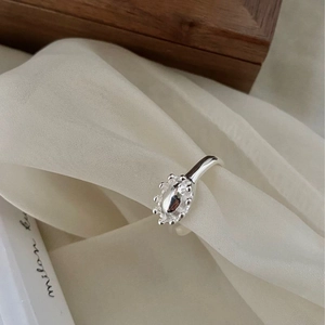 Detail shot of a polished S925 sterling silver floral oval crown ring on silk