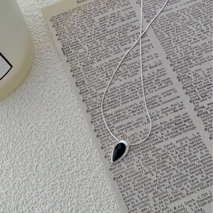 Détail du collier goutte argenté avec pierre noire sur un dictionnaire anglais