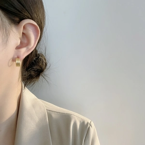 Gros plan de boucles d'oreilles créoles dorées à triple couche portées par un mannequin