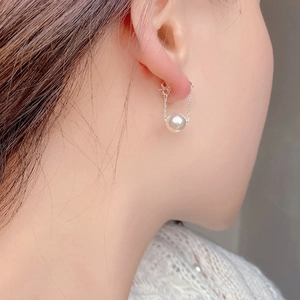 Detailed view of round white pearl earrings with U-shaped double chain on silver base