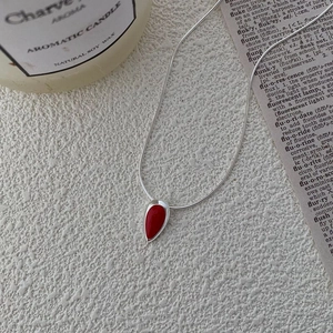 Gros plan du collier en argent S925 avec un pendentif goutte d'eau serti de pierre rouge