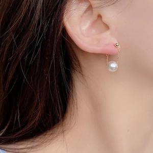 Elegant round pearl earrings on a gold chain, featuring a wrap-around floating design