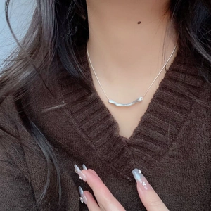 Close-up of a 925 silver irregular bar pendant with a brushed finish on a model necklace