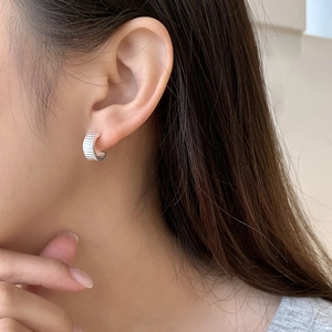 Close-up of S925 sterling silver pleated gear-shaped C-hoop earrings on model ear