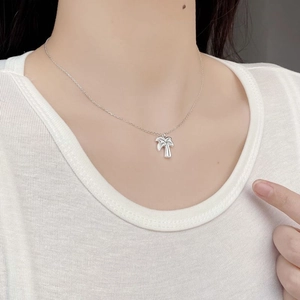 Close-up of minimalist S925 sterling silver palm tree pendant necklace on woman's neck